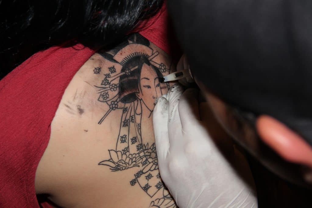 Ein Tattooartist arbeitet an einem Geishatattoo