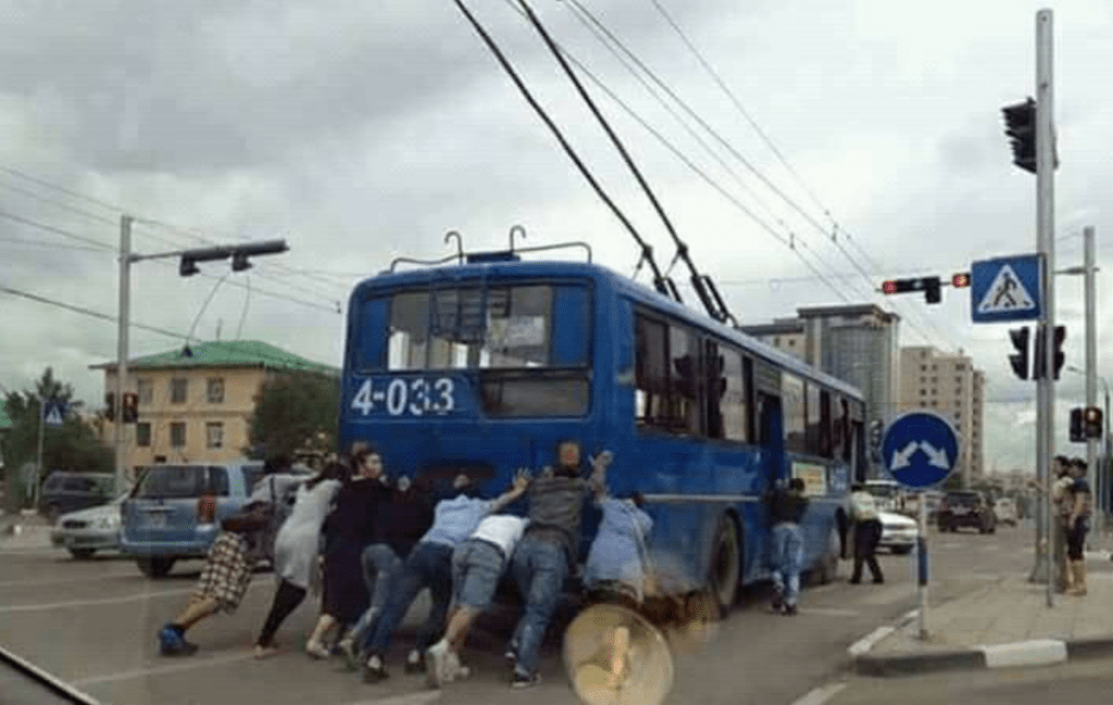Menschen schieben einen Oberleitungsbus in der Mongolei an